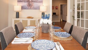 A dining table set with blue and white patterned plates, silverware, and clear glassware. - The Bluebonnet - Pet-Friendly Historic 3BR Home in Downtown McKinney (McKinney)