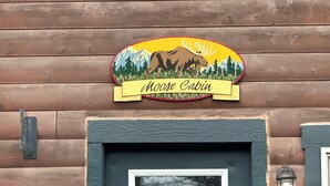 Una cabaña de madera con un logotipo de alce y la leyenda 'Moose Cabin' en la pared.