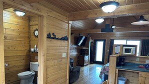 Ein Interieur einer Holzhütte mit Bad, Essbereich und Küchenzeile.