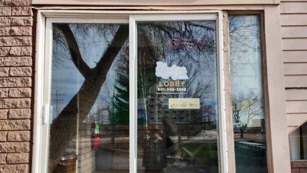 Et vindue med et skilt, der viser 'Lodge Lobby' og et telefonnummer.