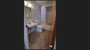 Et badeværelse med vask, toilet og bruseområde.
