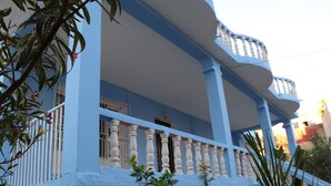 Ein Gebäude mit blauer Fassade, weißen Säulen und einem Balkon mit weißen Brüstungen.