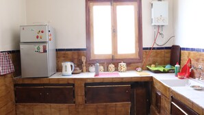 Eine Küche mit Kühlschrank, Fenster, Warmwasserbereiter und diversen Küchengeräten.