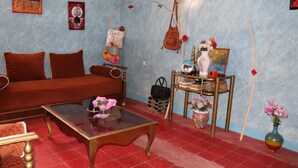 Ein gemütliches Wohnzimmer mit einem roten Sofa, einem Glastisch und einem Holztisch mit Blumen.'