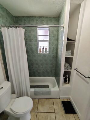 Ein Badezimmer mit Dusche, Toilette und Fenster.