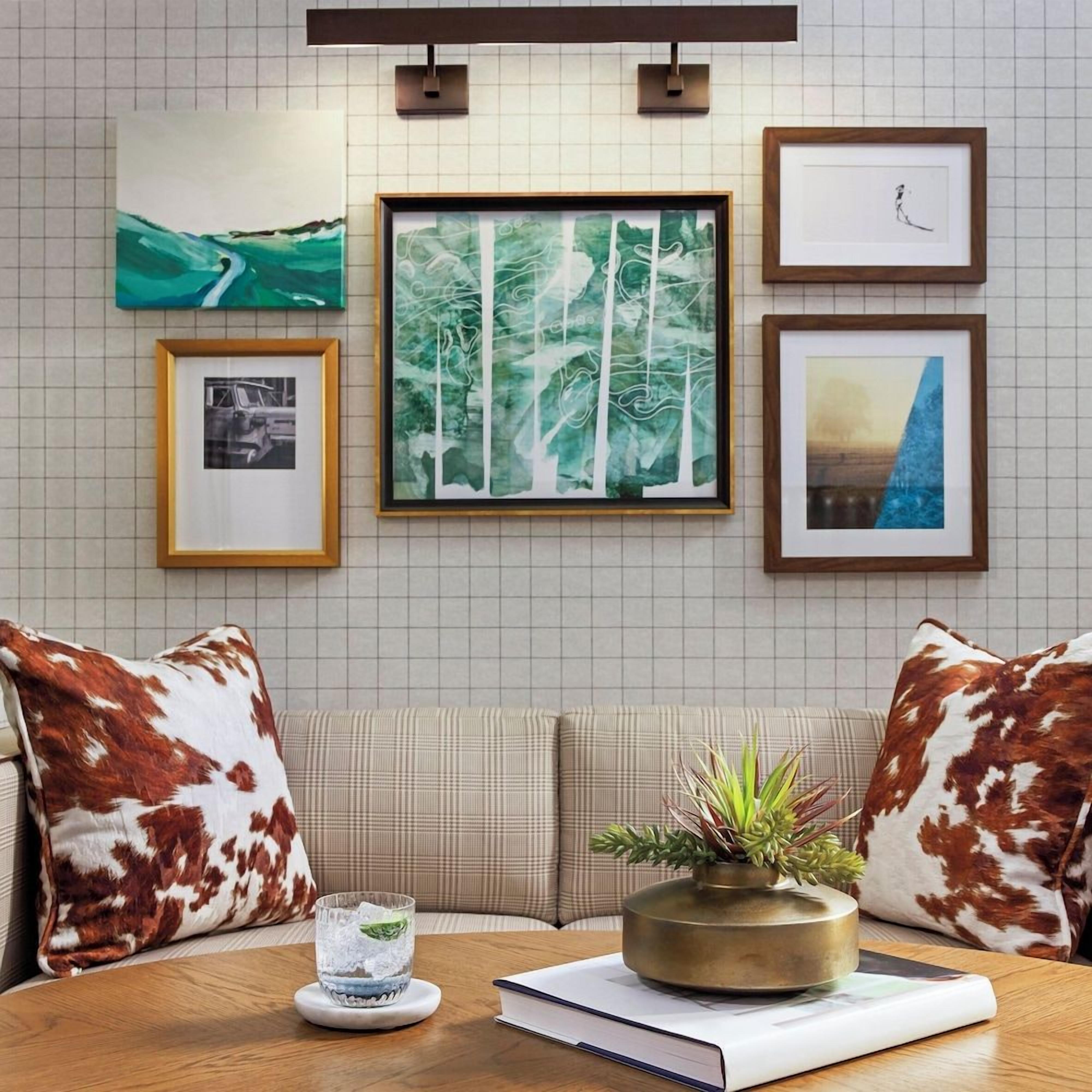 A room with a sofa, a coffee table with a book and a plant, and framed artwork on the wall.