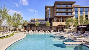 A modern hotel with a large pool area, multiple balconies, and a clear blue sky. - King Room at a 5⭐️ Hotel (Frisco)
