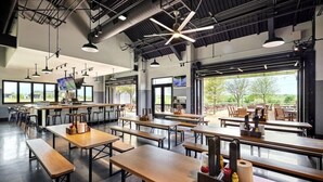A modern restaurant with high ceilings, exposed beams, and natural light from large windows. - King Room at a 5⭐️ Hotel (Frisco)