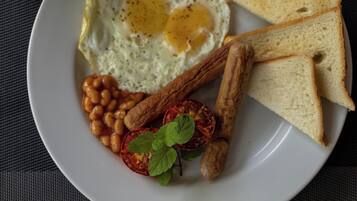 Un plato con huevos fritos, frijoles, tostadas y una rodaja de tomate.