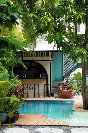 A pool area with a bar, surrounded by lush greenery and a staircase. - Zinnia Villa (Maafushi)