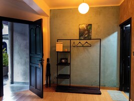 Una habitación con un armario negro, un estante pequeño con una radio y un perchero.