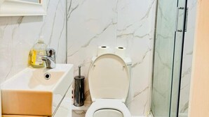 Un baño con inodoro, lavamanos y cabina de ducha de vidrio.