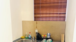 Una kitchenette compacta con lavamanos, estufa y refrigerador pequeño.