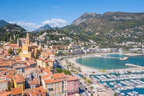 A coastal town with a marina, a prominent church, and a mountainous backdrop. - Garden View Daturas, Menton, France (Menton)