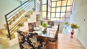 Un'ampia zona giorno con una scala, un tavolo da pranzo apparecchiato con sedie e vasi decorativi.