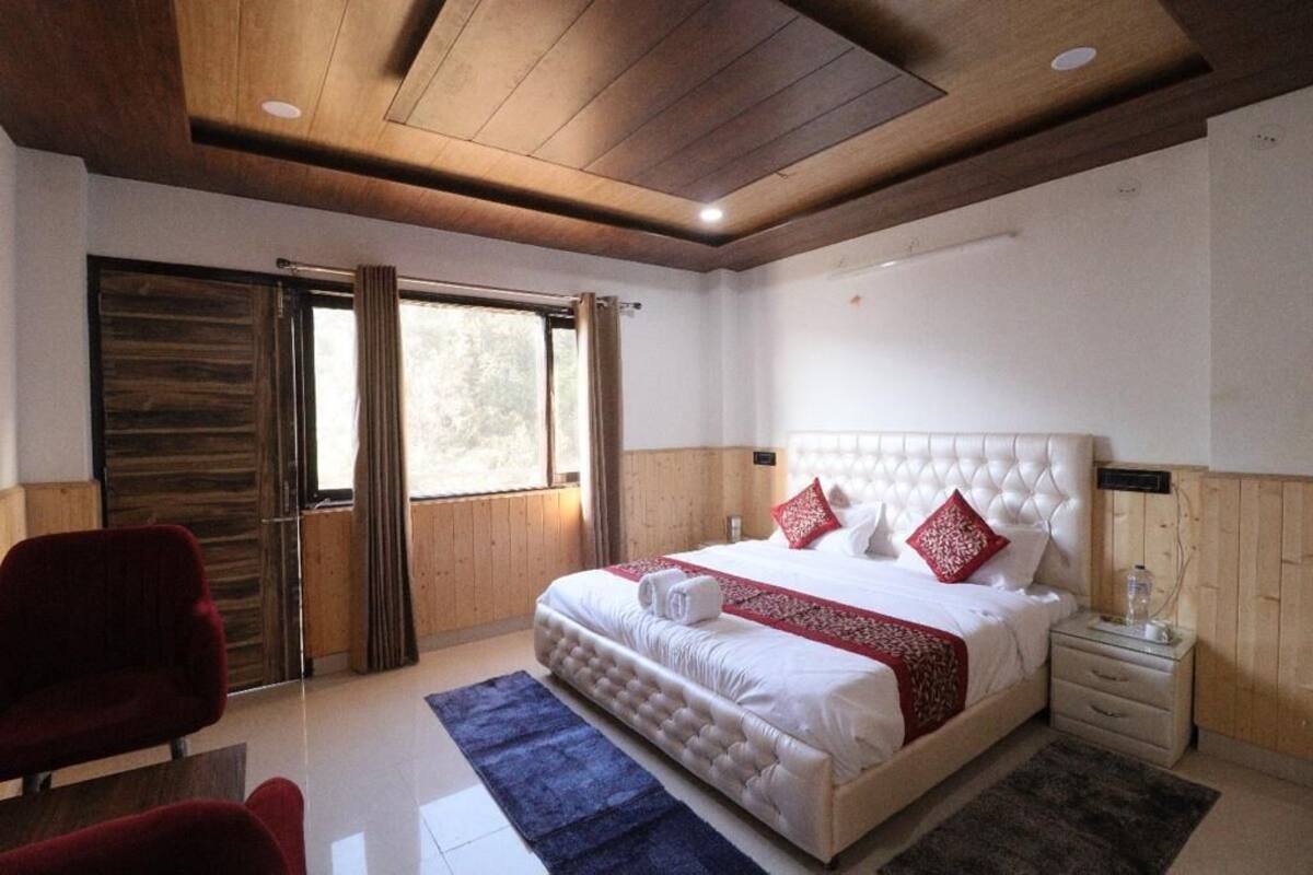 A bedroom with a large bed, wooden ceiling, and a window with curtains.