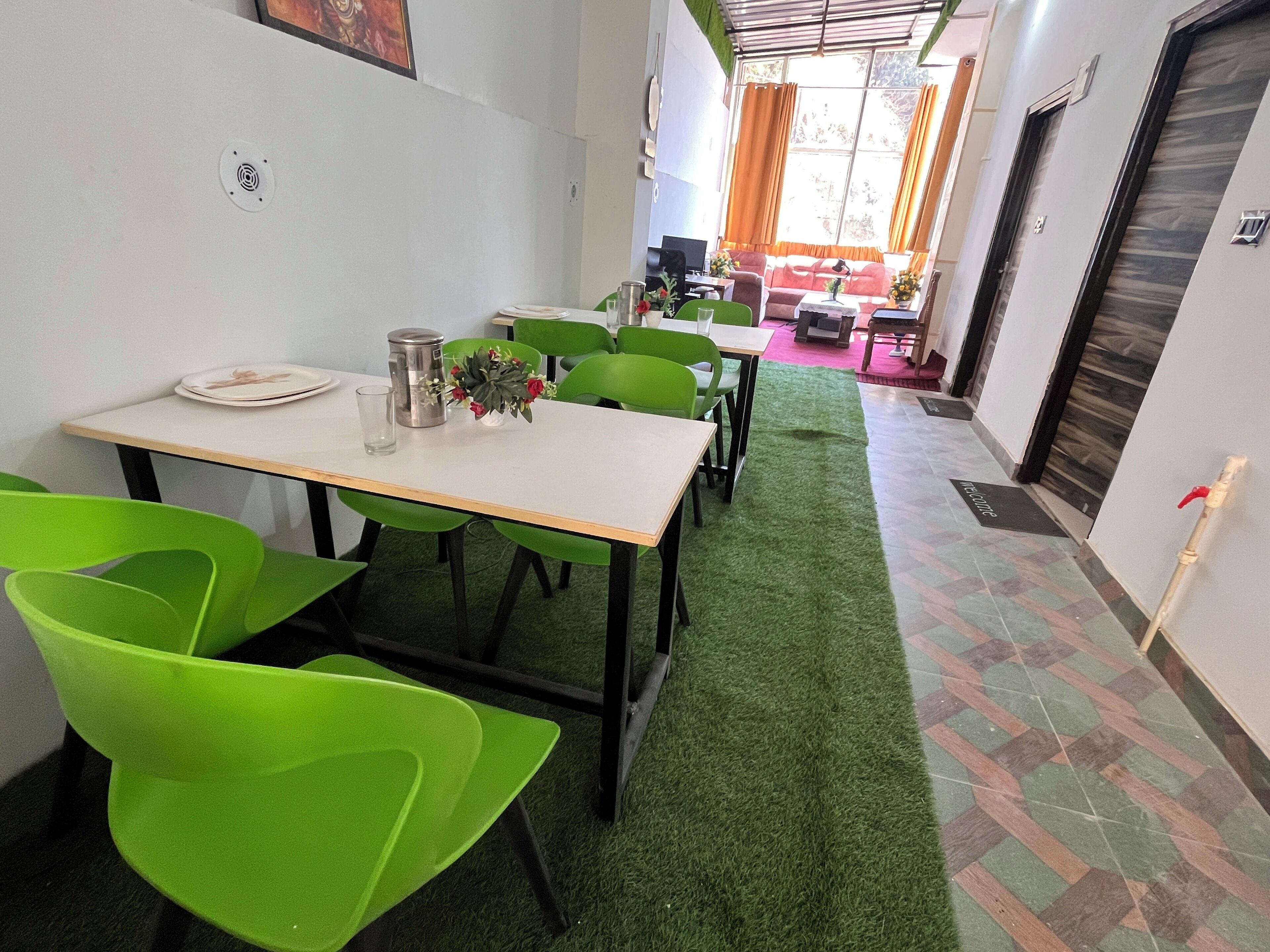 A dining area with green chairs, a white table, and a small vase with flowers.