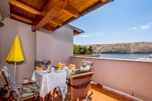 A balcony with a table set for breakfast, overlooking a lake and hills. - Sunset By The Sea /w Sea View Balcony, Lopar, Croatia (Lopar)