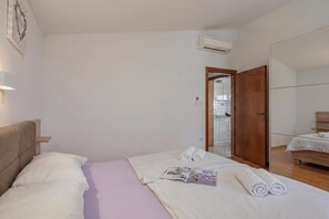 A hotel room with a bed, a bedside table, a mirror, and an air conditioning unit. - Sunset By The Sea /w Sea View Balcony, Lopar, Croatia (Lopar)