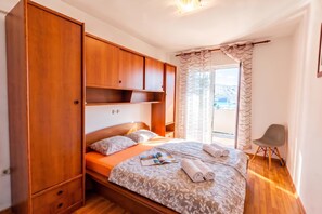 Ein Schlafzimmer mit einem Bett, einem Holzschrank und Blick ins Freie.