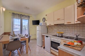 Cozinha compacta com área de refeições, equipada com micro-ondas, forno e pia.