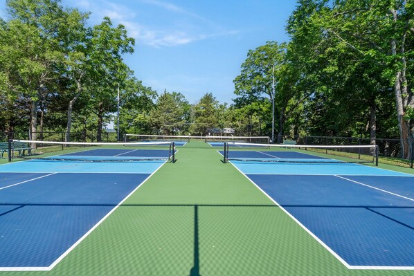 A tennis court with a net, surrounded by trees.