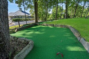 Een minigolfbaan met een groen kunstgazon, stenen randen en een rode golfbal.