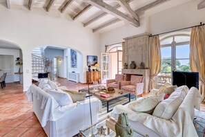 A spacious living room with a fireplace, white sofas, and a view of the outdoors. - Villa Tortue - Private pool & Sea view, Grimaud, France (Grimaud)