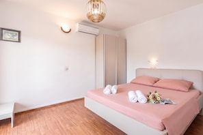 Une chambre moderne avec un lit, des lampes de chevet, un appareil de climatisation et un plancher en bois.