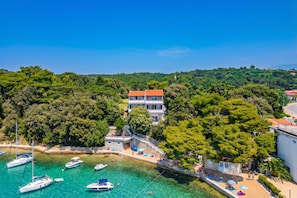 A coastal property with a large building, a dock with boats, and a beach area.