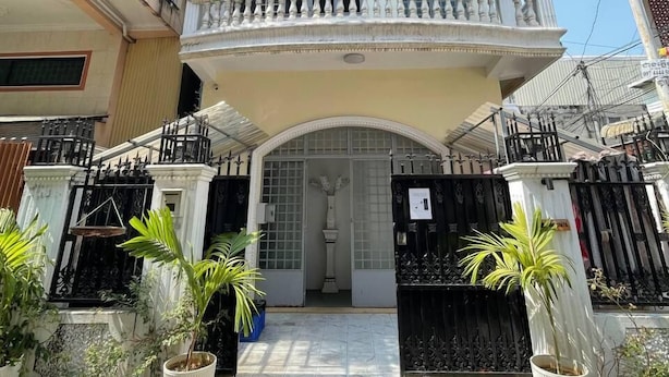 A two-story building with a balcony, a gated entrance, and potted plants. - Dimocrata (Phnom Penh)