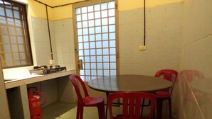 A small, enclosed room with a round table and four red chairs. A fire extinguisher is visible on the floor. - Dimocrata (Phnom Penh)