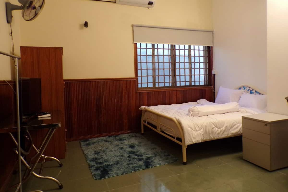 A bedroom with a bed, bedside table, and a window with blinds.