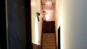 A narrow hallway with a wooden staircase leading to a door at the end. - Dimocrata (Phnom Penh)