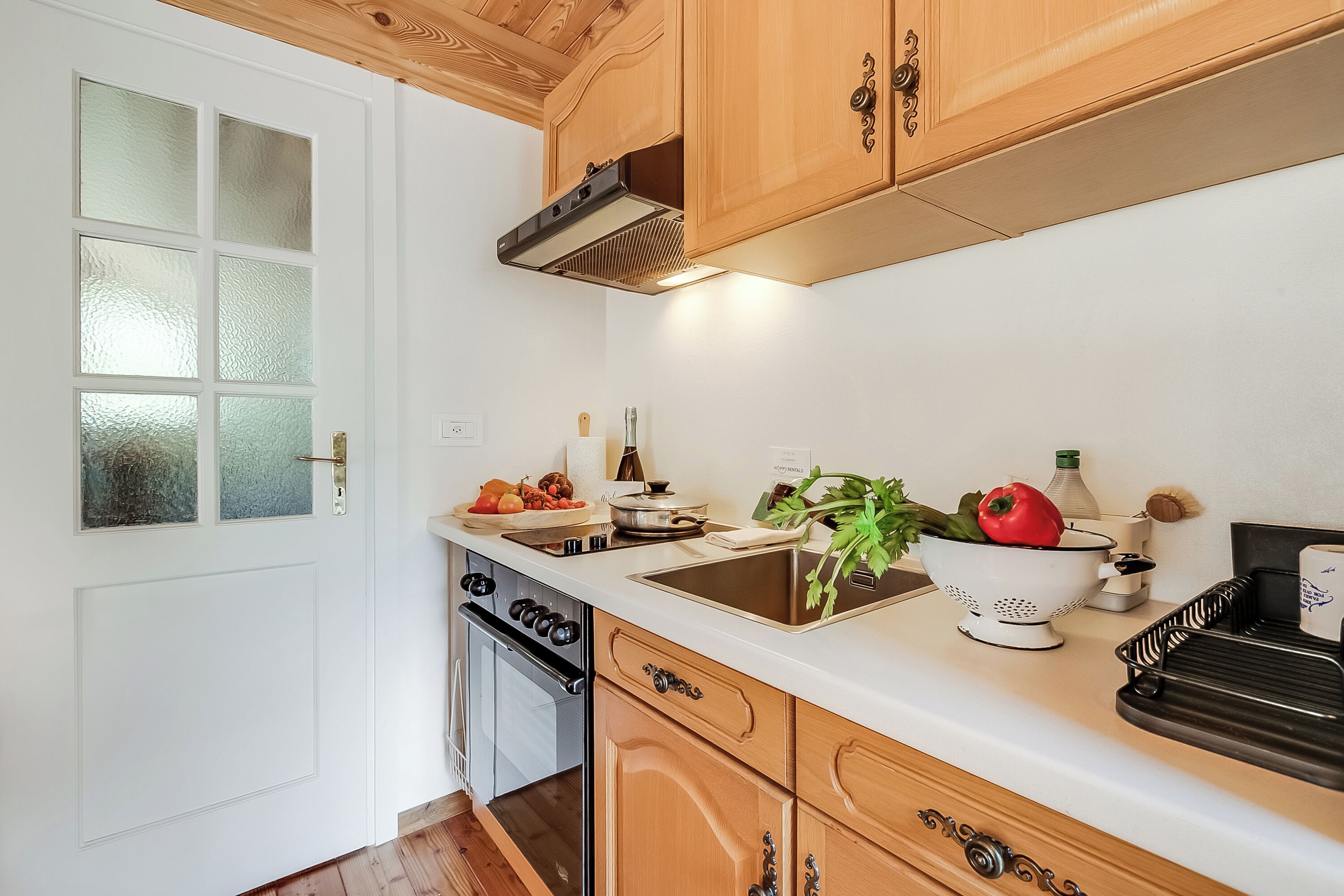 A kitchen with wooden cabinets, a stainless steel sink, and a dish rack.