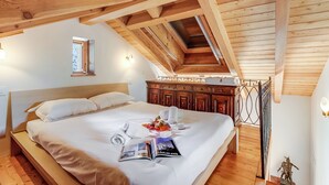 A neatly made bed with a magazine, towels, and a small statue on a wooden floor. - Mille Colline la Casa 1 with Shared Pool, Pianezzo, Switzerland (Pianezzo)
