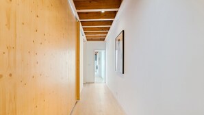 Een gang met houten wanden en een houten plafond, die leidt naar een kamer met een deur aan het einde.