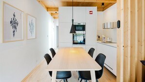 Een moderne keuken met witte kasten, een inbouwoven en een zwarte hanglamp.
