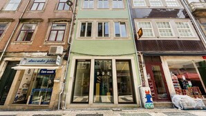 Een rij meerverdiepinggebouwen met verschillende winkelpanden, waaronder een juwelierzaak en een winkel met een rode deur.