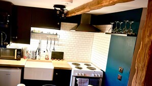 A kitchen with a microwave, stove, and various utensils. - Quaint and Cosy Cottage - Manchester (Bury)