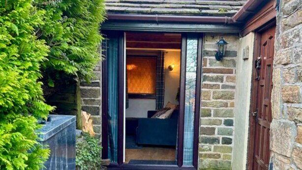 A stone building with a wooden door and a small porch. - Quaint and Cosy Cottage - Manchester (Bury)