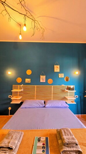 Une chambre d’hôtel avec un lit, une tête de lit en bois, des lampes fixées au mur et un mur orné de motifs circulaires.