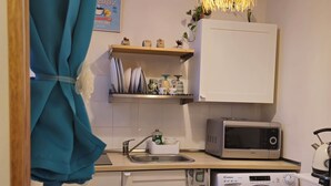 A compact kitchen with a microwave, washing machine, and a hanging light fixture. - Gorgeous apartment near the metro (Torino)