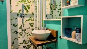 A bathroom with a shower, sink, and toilet, featuring teal walls and green ivy decorations. - Gorgeous apartment near the metro (Torino)