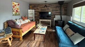 Un salon chaleureux avec un plancher en bois, un canapé, une table basse et un téléviseur.