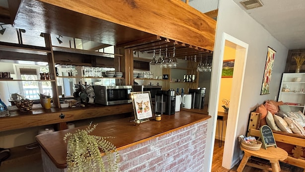 Un coin bar au style rustique, avec un comptoir en briques, un plafond en bois et des luminaires suspendus.