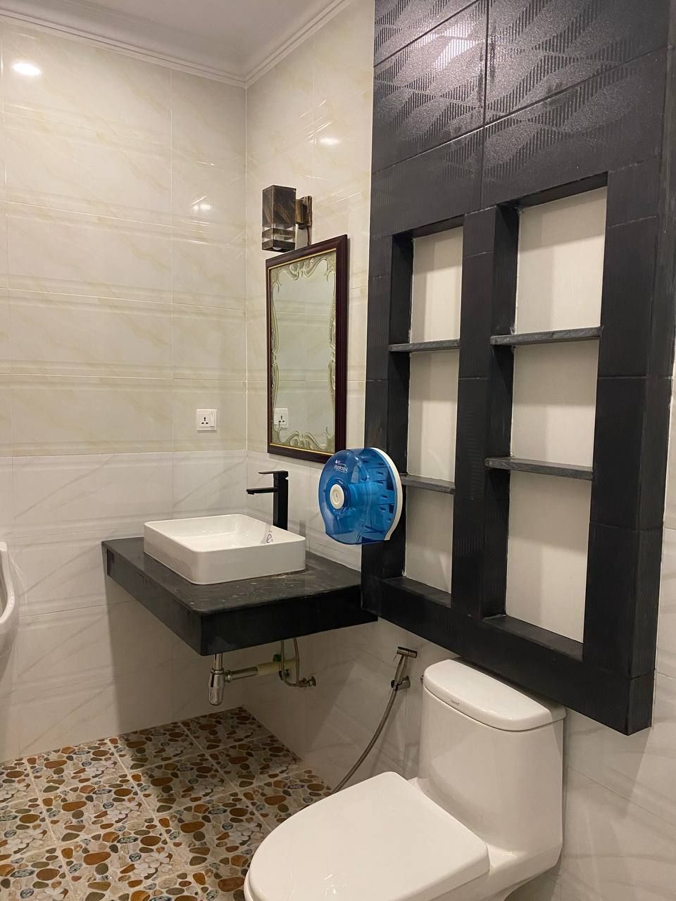 Une salle de bain avec des toilettes blanches, un lavabo blanc et un ventilateur bleu.