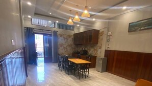 Amplia sala de estar con piso de mármol, una mesa de comedor de madera con sillas, un sofá y una zona de cocina con armarios.