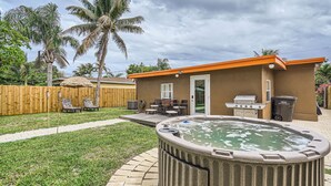 A backyard with a hot tub, outdoor furniture, a grill, and a wooden fence. - Spacious 3BR Tropical Retreat - W/Hot Tub Near Beach, Downtown & Airport (West Palm Beach)