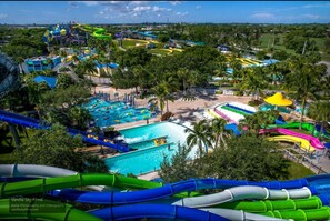 Un parc aquatique doté de nombreux toboggans et de plusieurs piscines, entouré de palmiers et de bâtiments.